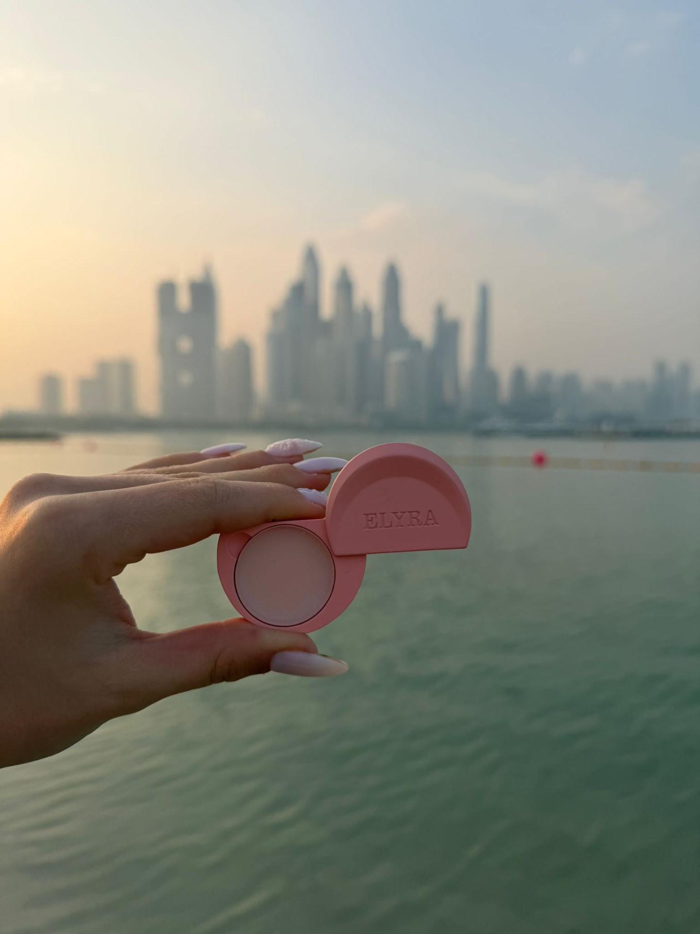 ELYRA rosa in mano davanti al panorama di Dubai